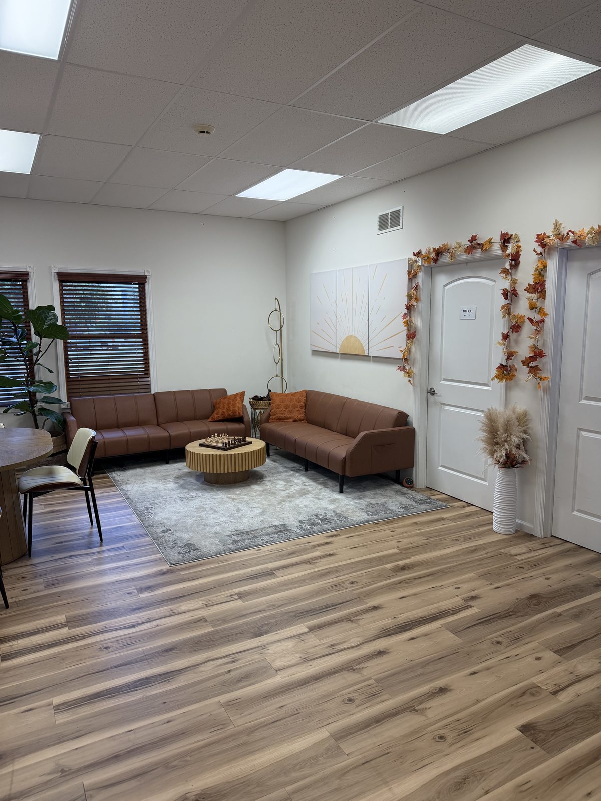 Client lounge with two brown sofas, a round coffee table, and a rug